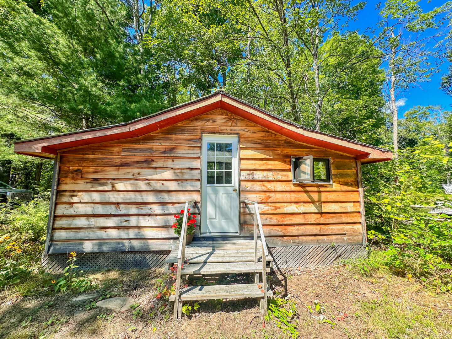 A small wood bunkie in front of green trees