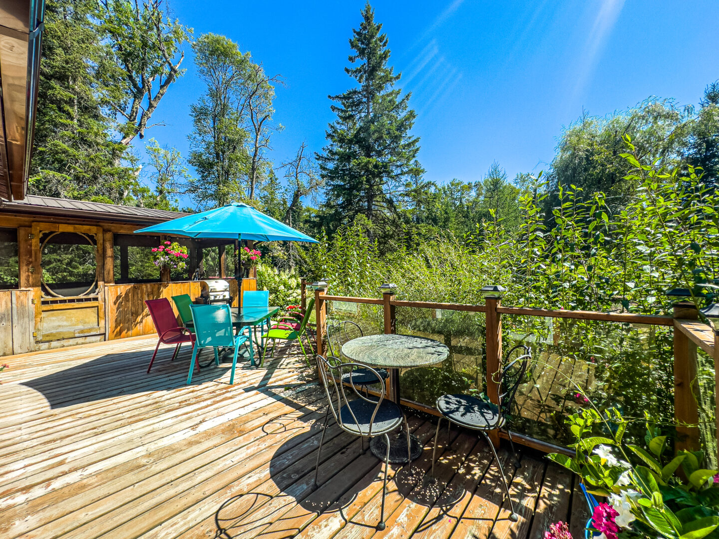 A wood deck with a small patio set and a teal patio umbrella