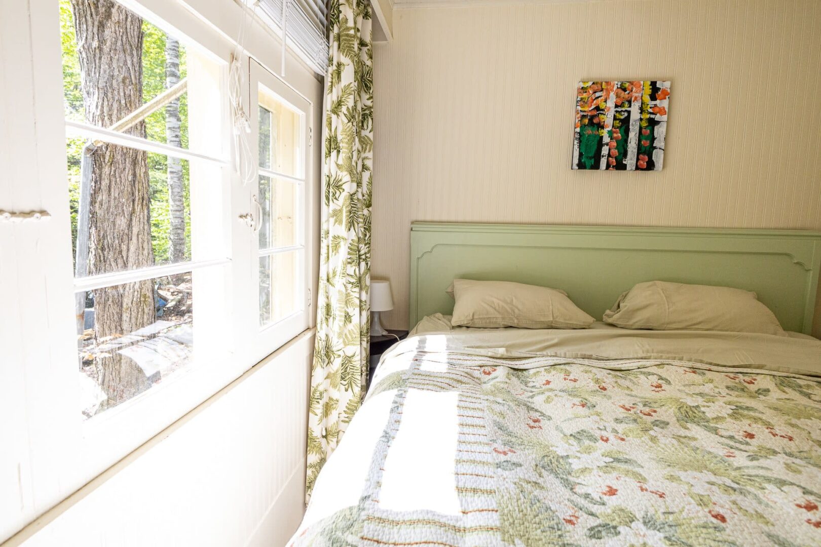 A white bed on a green bed frame in a white bedroom
