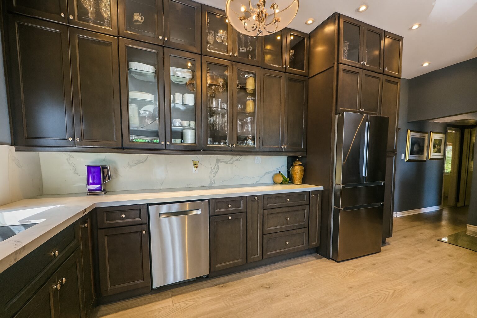 A kitchen with dark brown cabinets and a metallic dishwasher