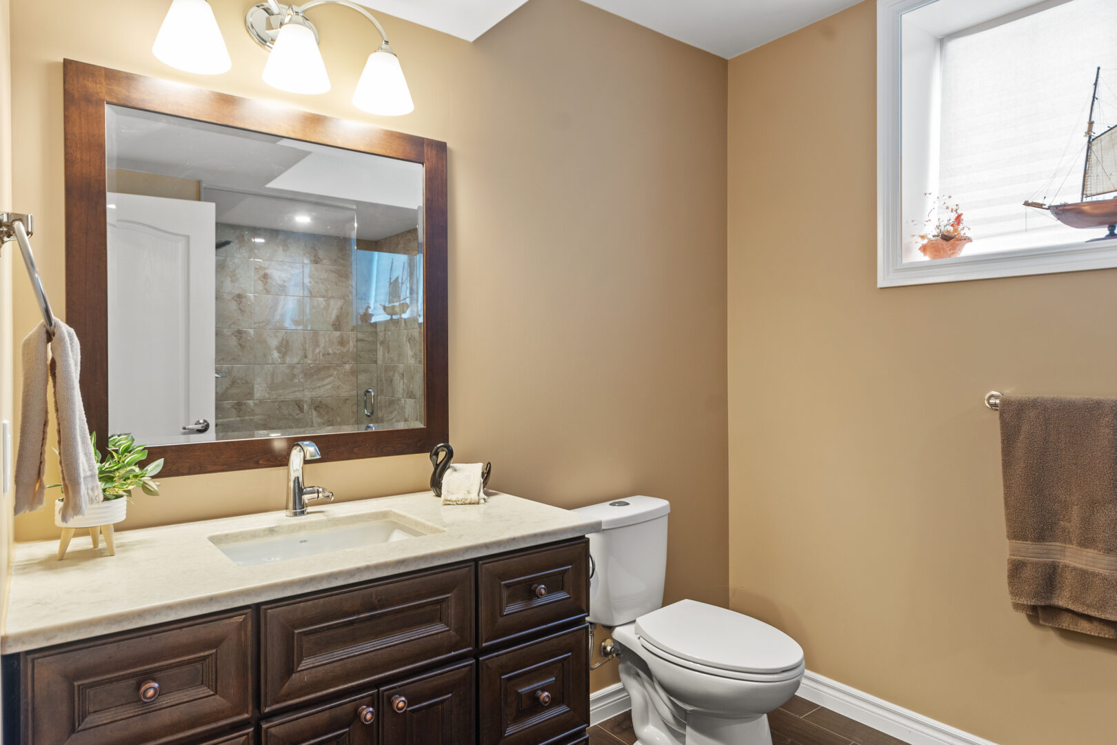 A beige bathroom with a dark brown vanity