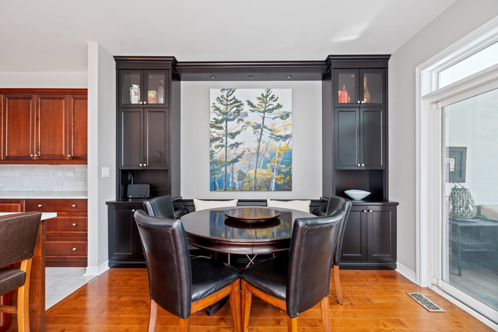 A round black dining table with black chairs in front of a window