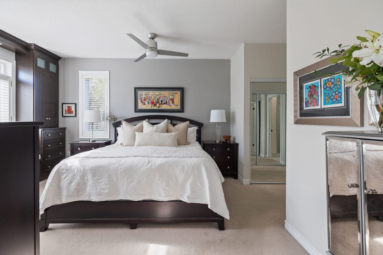 A white bed on a dark brown bed frame in a grey bedroom