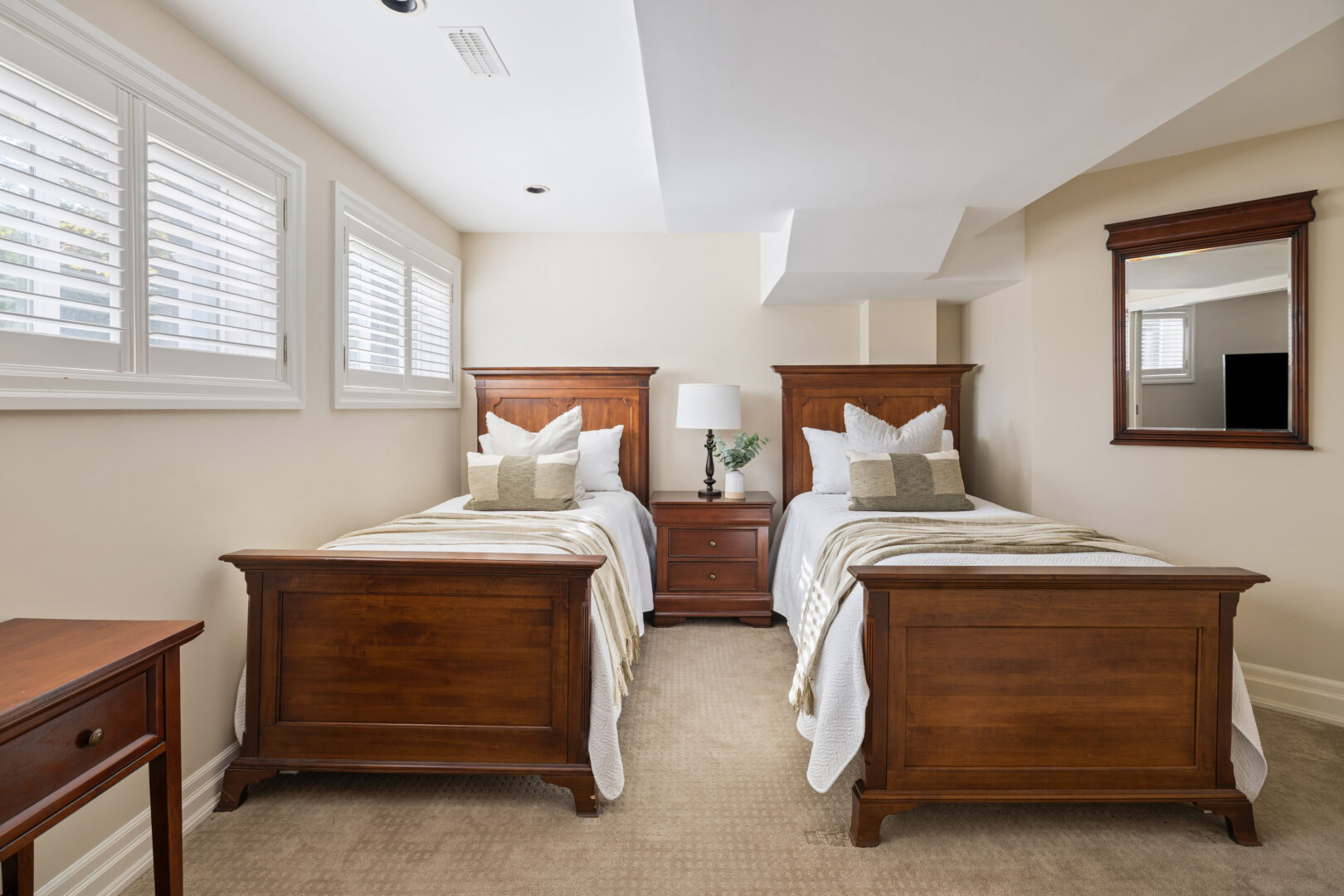 Two twin beds on wood frames in a white bedroom