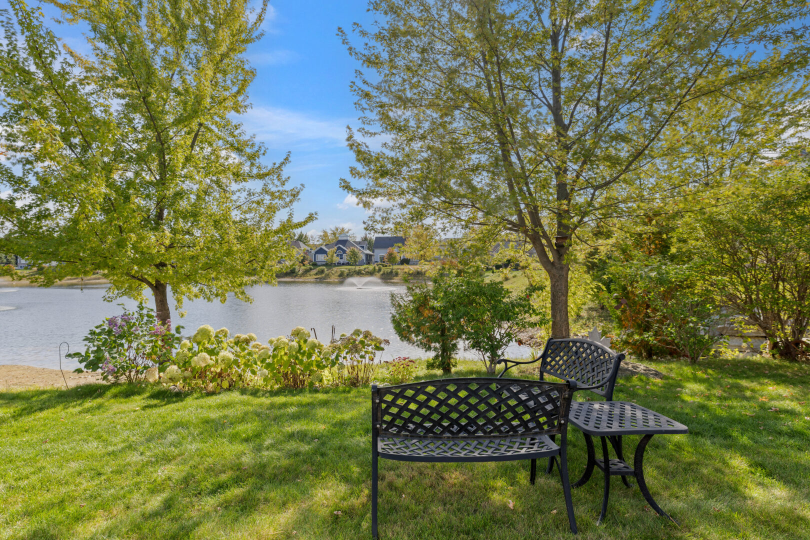 A metal bench on a grassy area by water