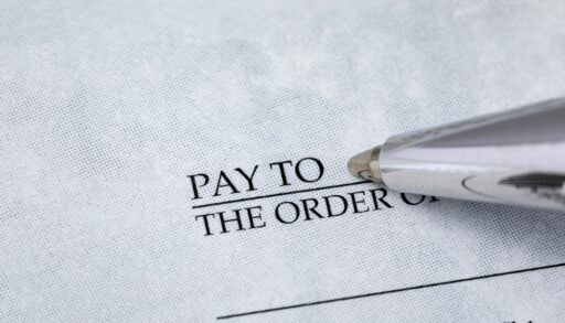 Writing check with pen. Banking, paying bills, and financial fraud concept