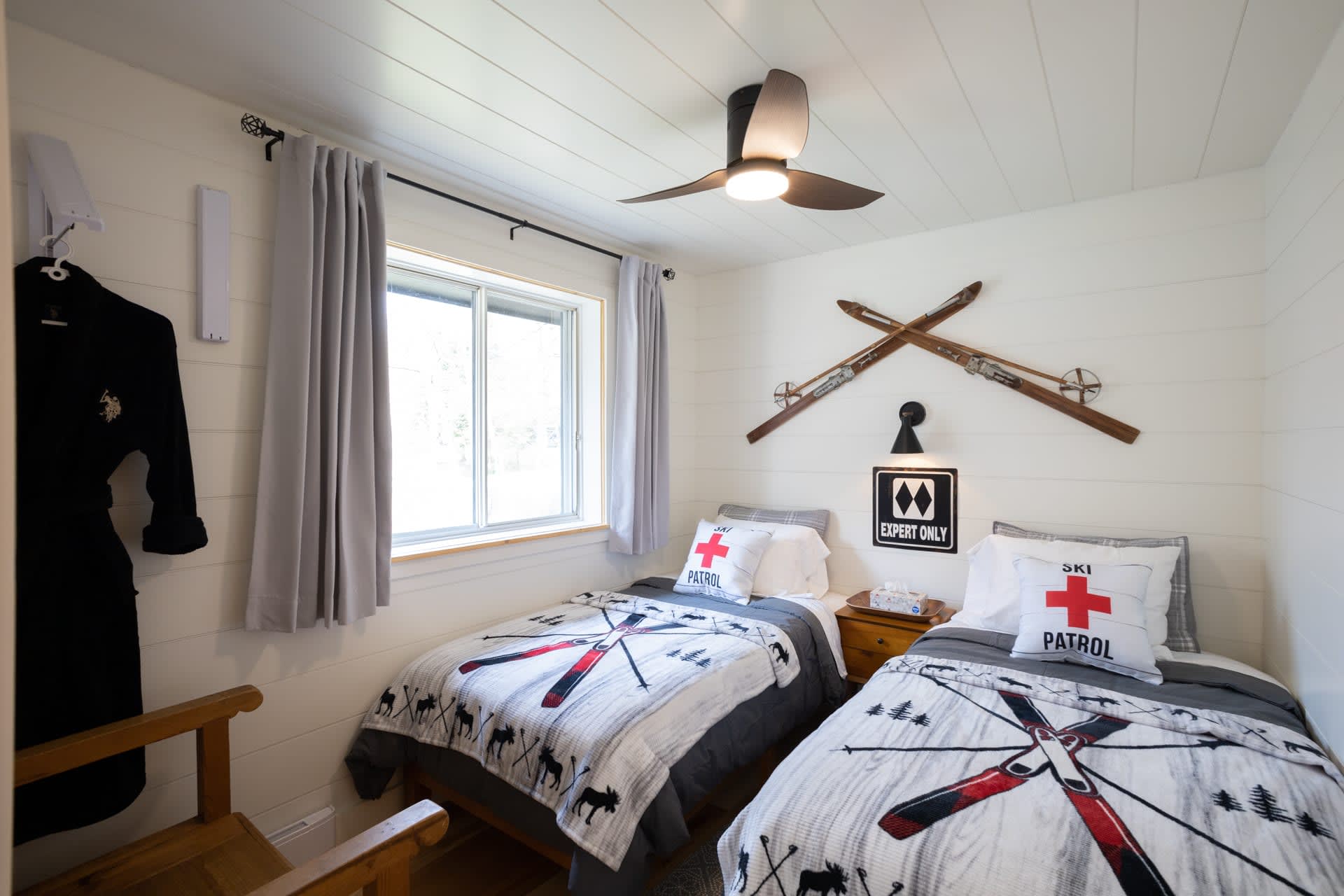Two twin beds next to each other in a white bedroom. They're both covered in windmill themed bedspreads