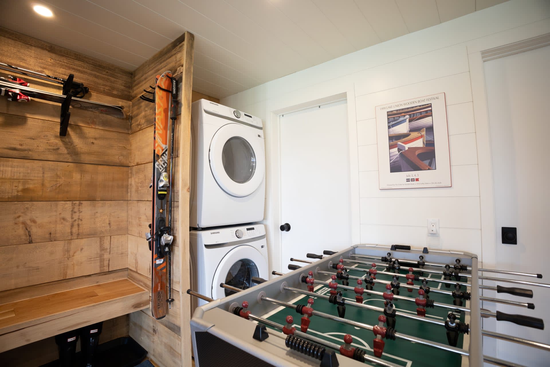 Stacked washing machines are nestled in a corner next to a foosball table