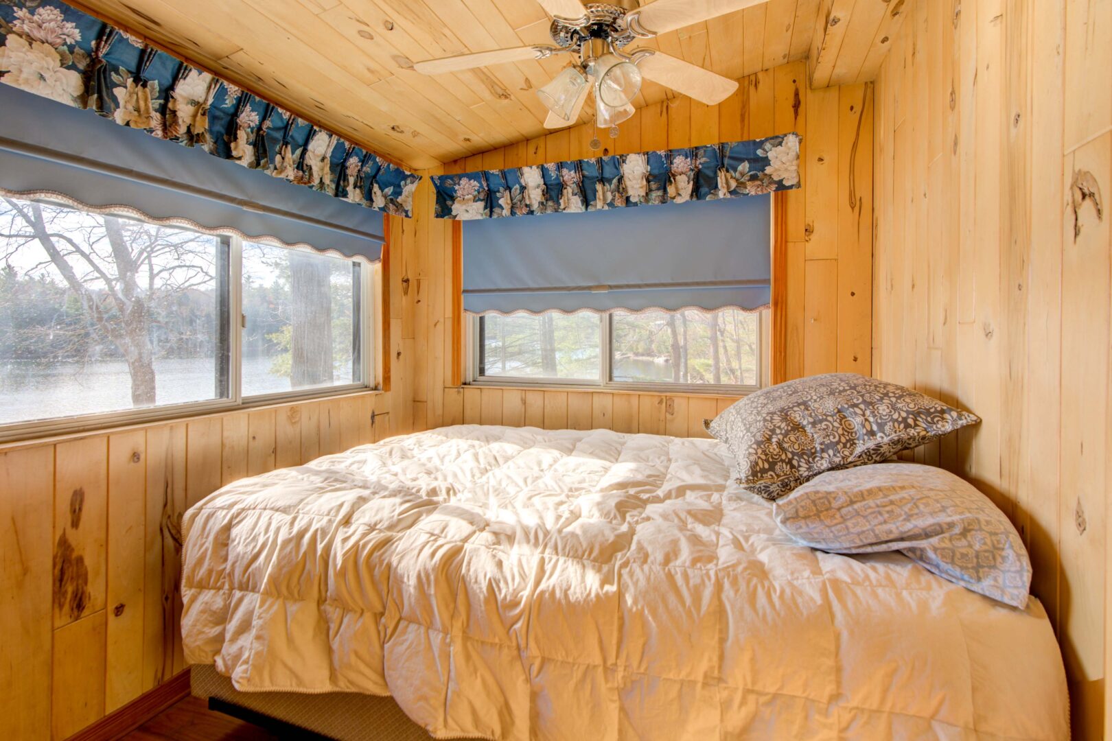 A white oversized bed in a light wood room with windows