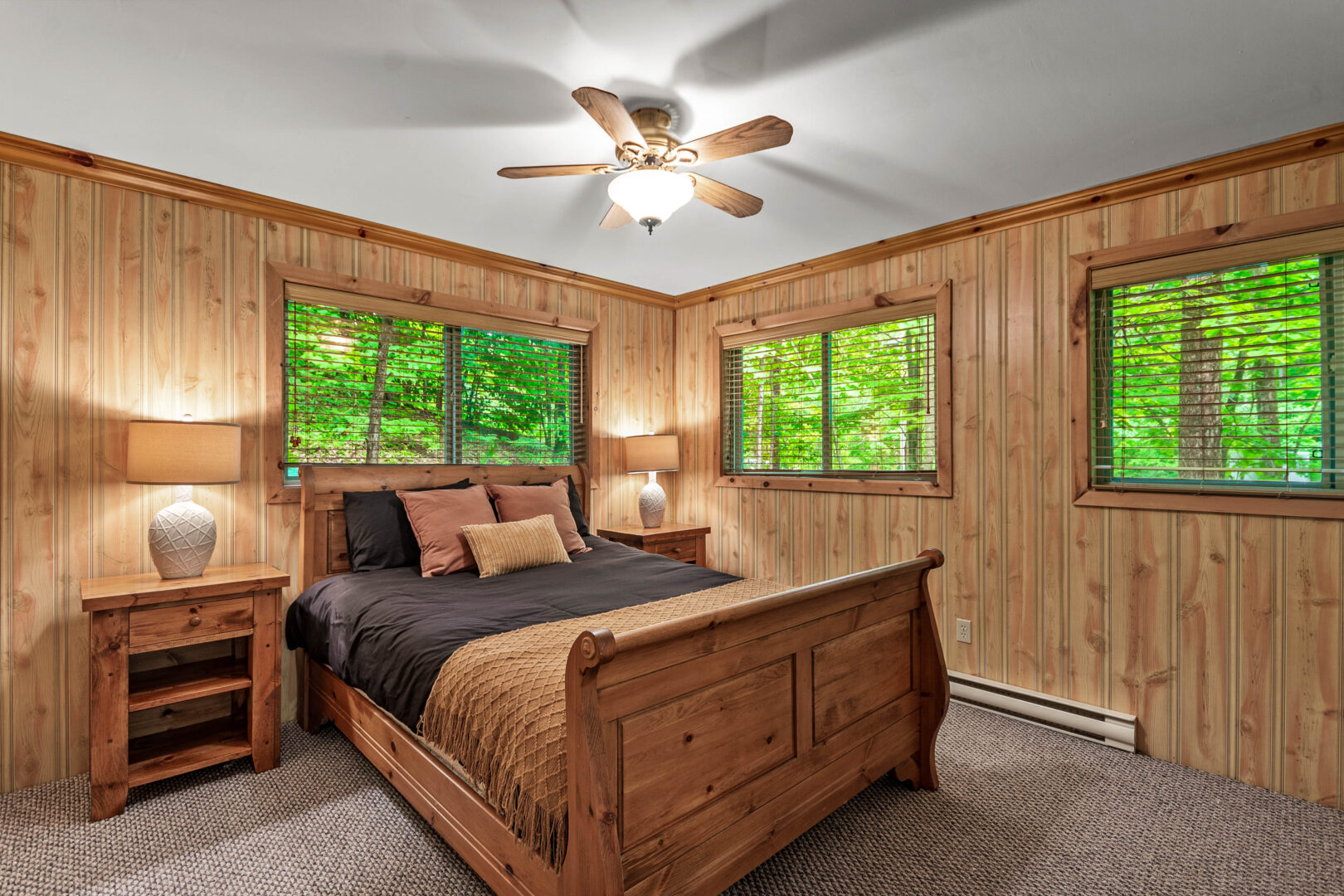 A wood sled bed with a black and brown duvet in a wood room