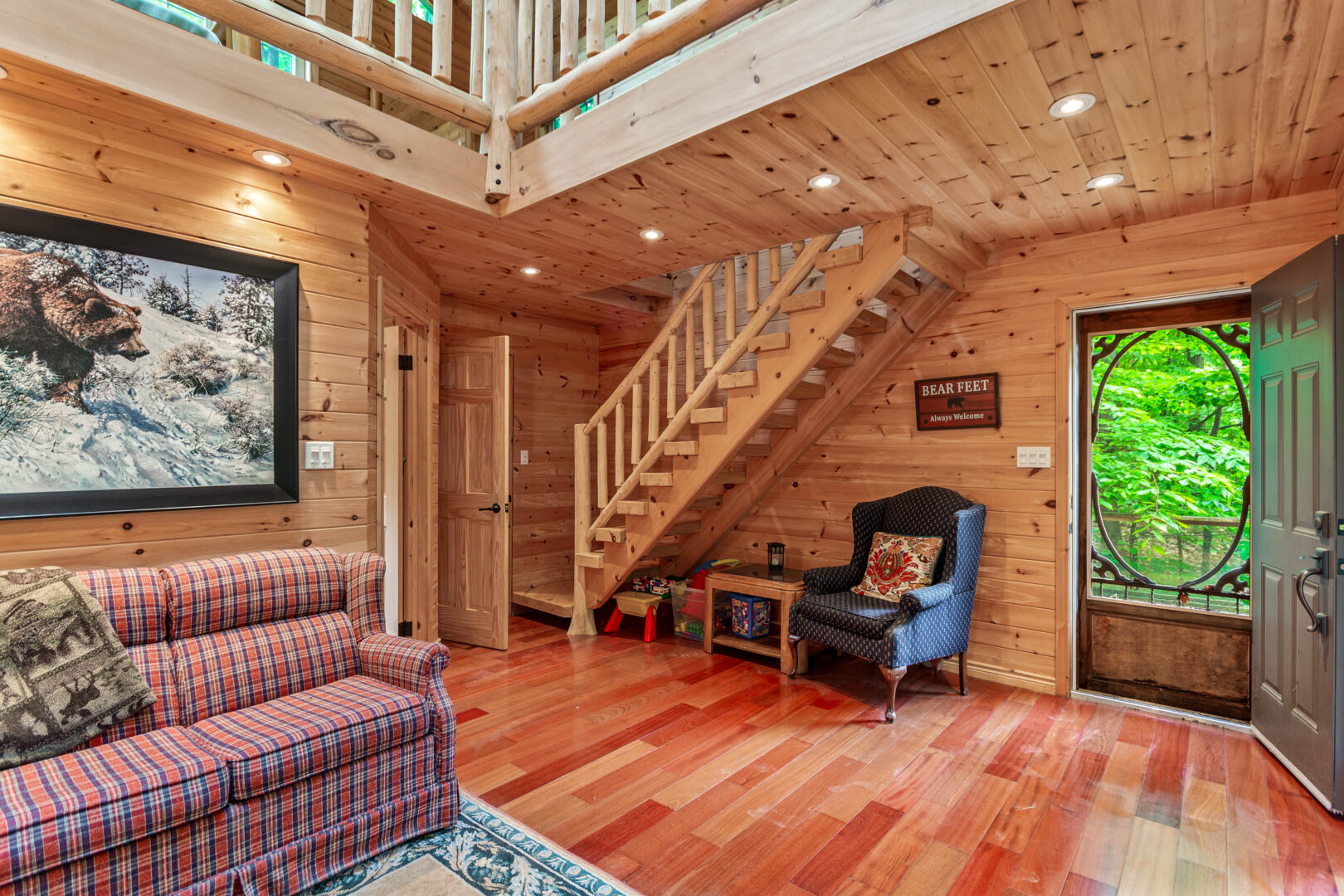 A living area with a red couch and blue chair. Wood steps lead to a loft area