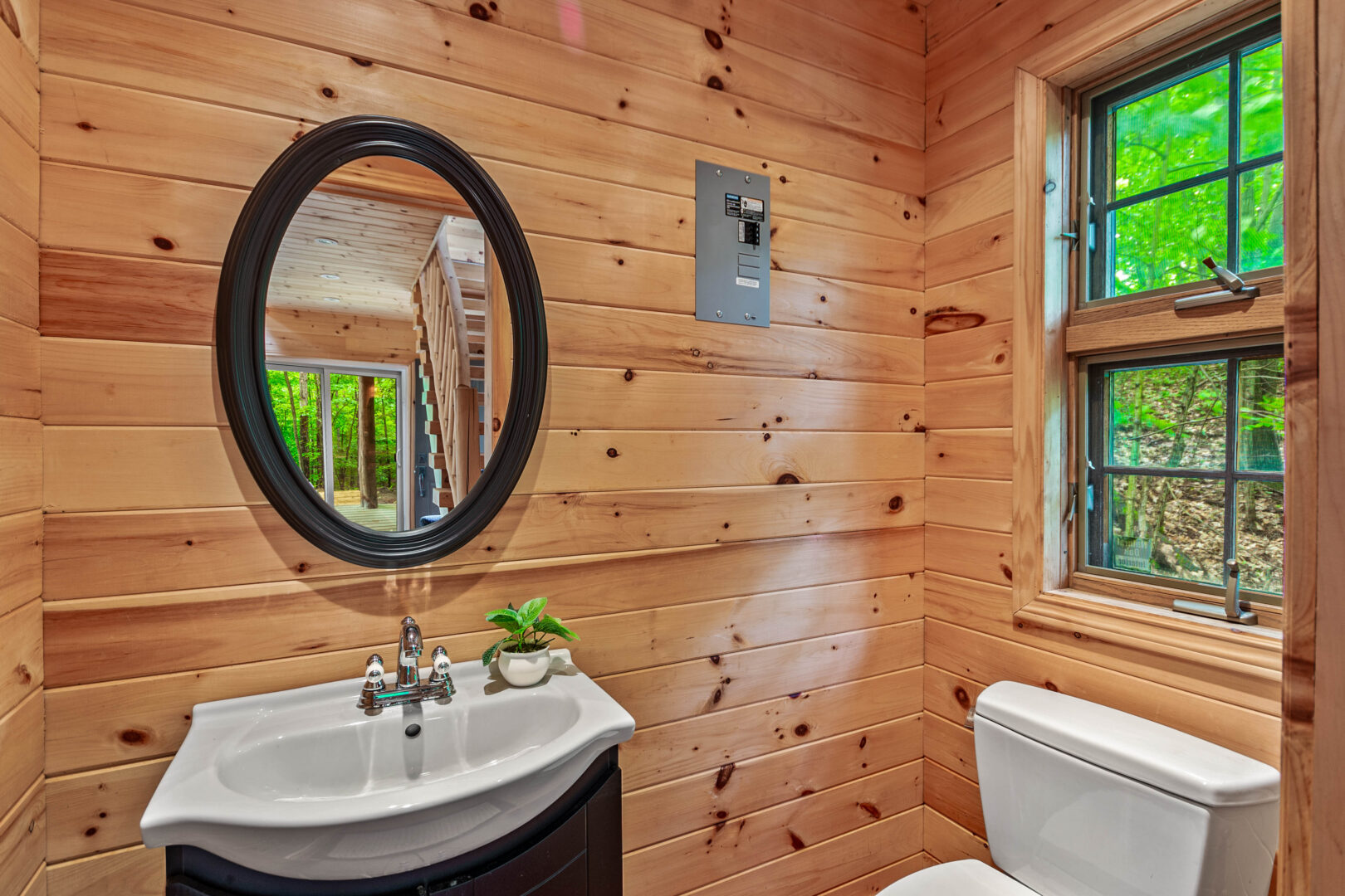 A wood paneled bathroom with a black vanity and round mirror