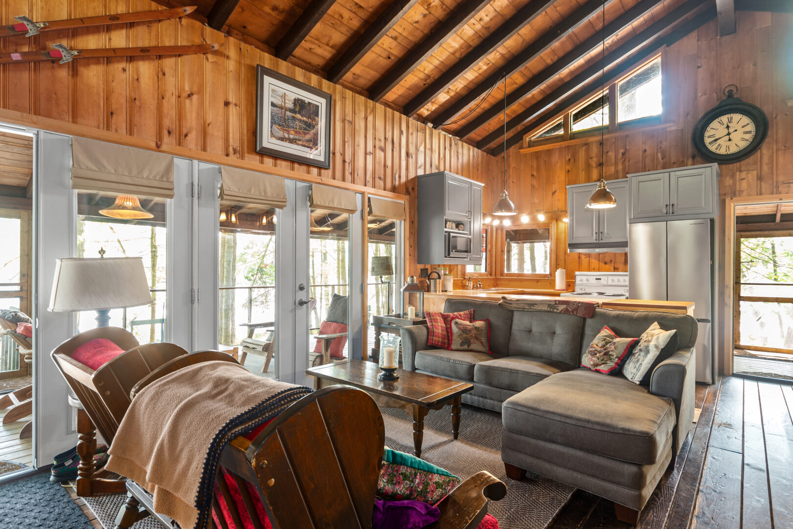 A grey couch faces a gred loveseat in a wood cottage