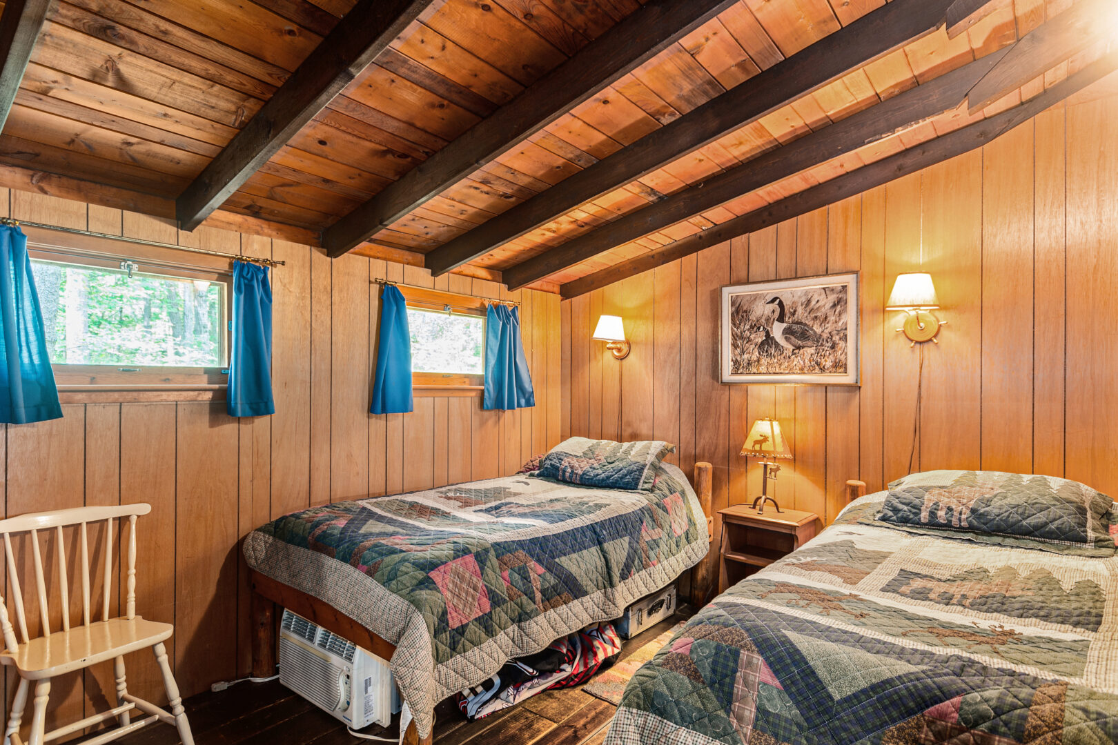 Two twin beds with patterned covers in a wood paneled room