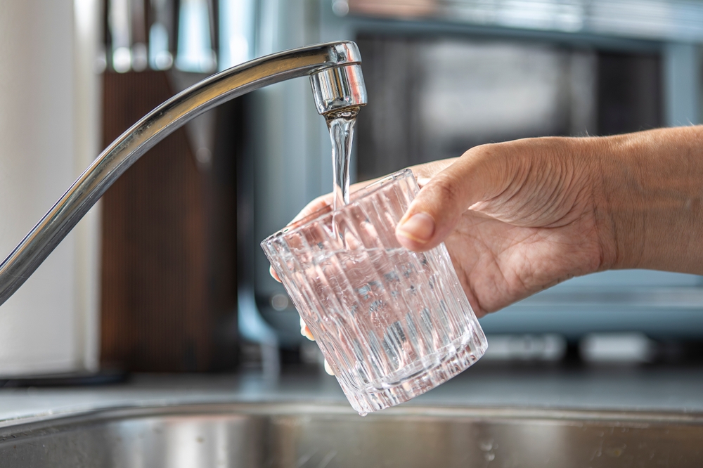 Closeup of a glass being filled with tap water in a kitchen, drinking water