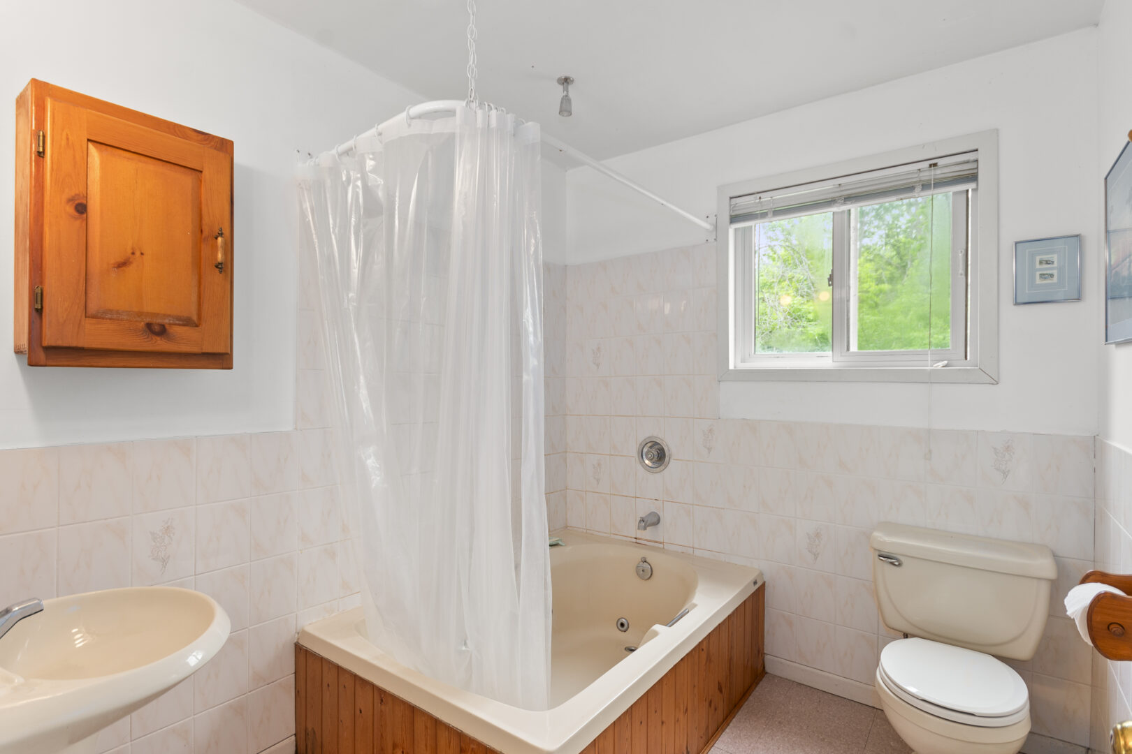 A white bathroom with a wood bathtub and a plastic shower curtain