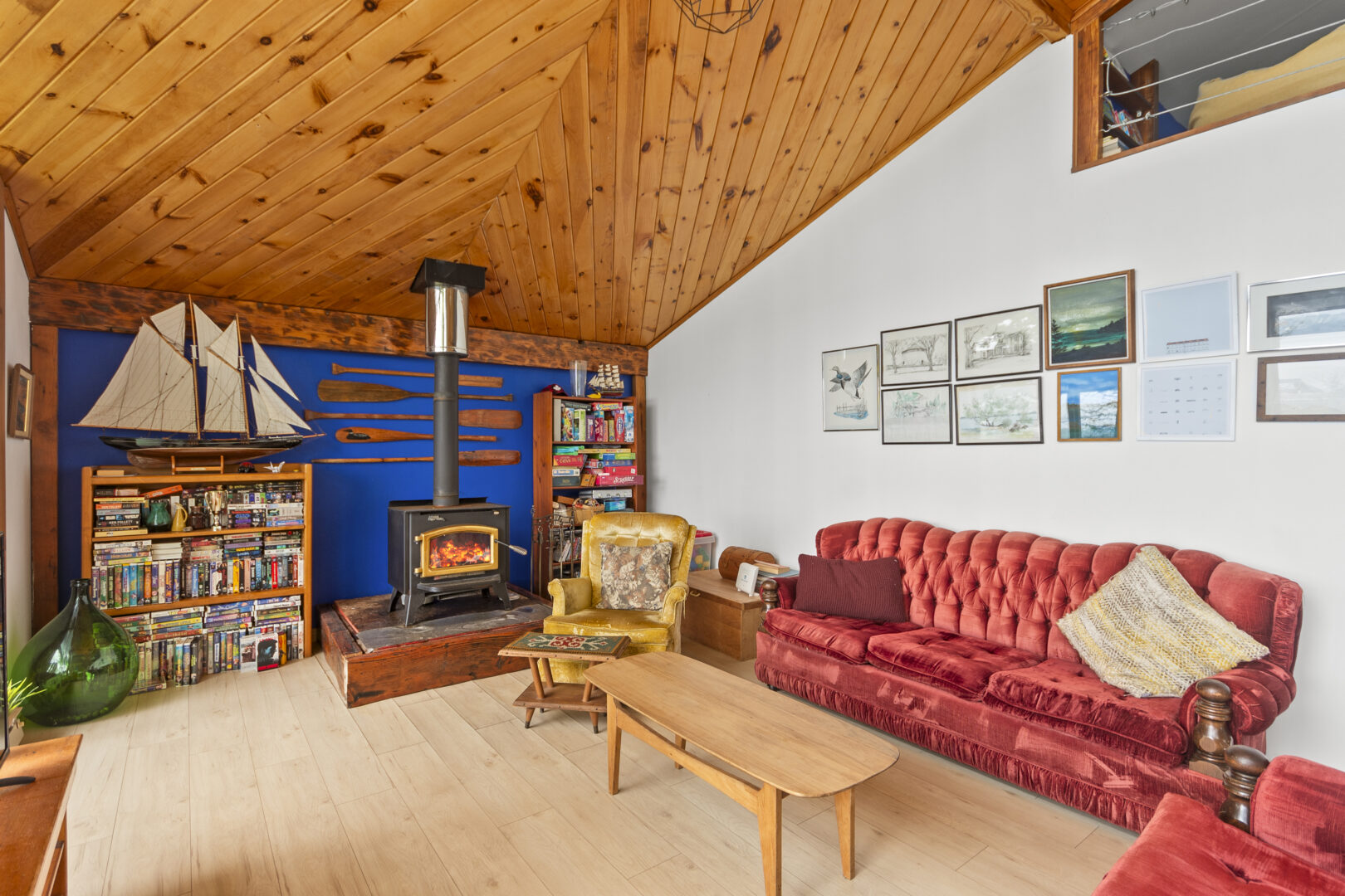 A wood stove in front of a cobalt blue wall in a cottage living room