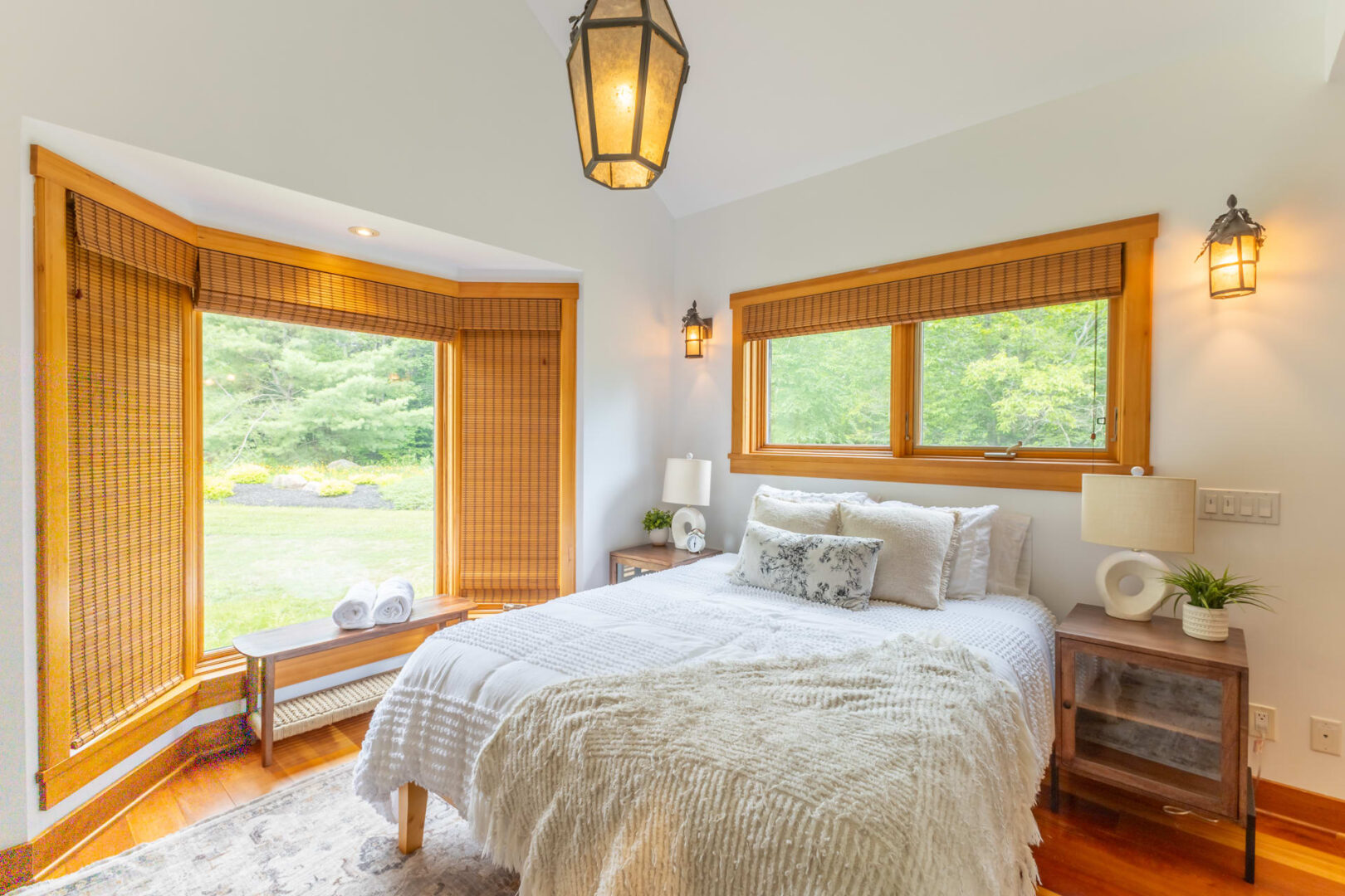 A white bedroom with a white bed and bright windows