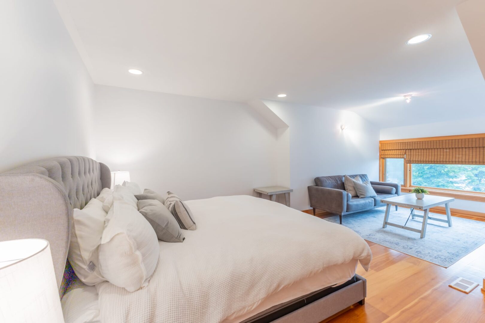 A white bed on a grey bed frame in a white bedroom