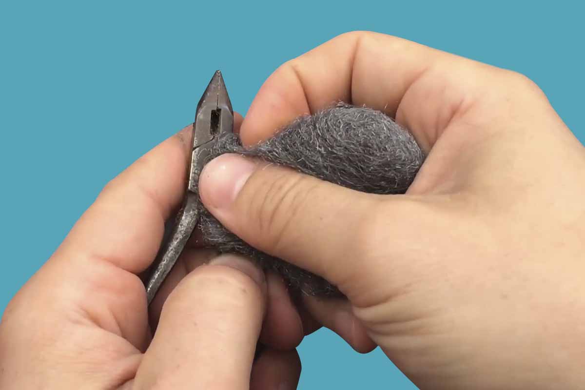 Closeup of hands using steel wool to scrub at a tool