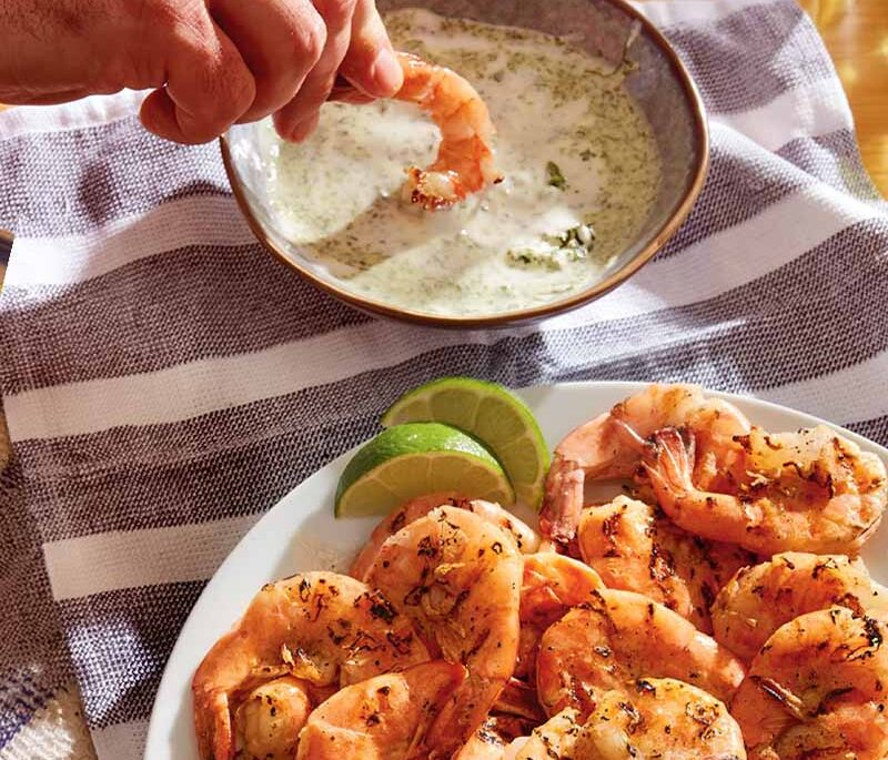 Grilled peel and eat shrimp with green goddess dip on a table