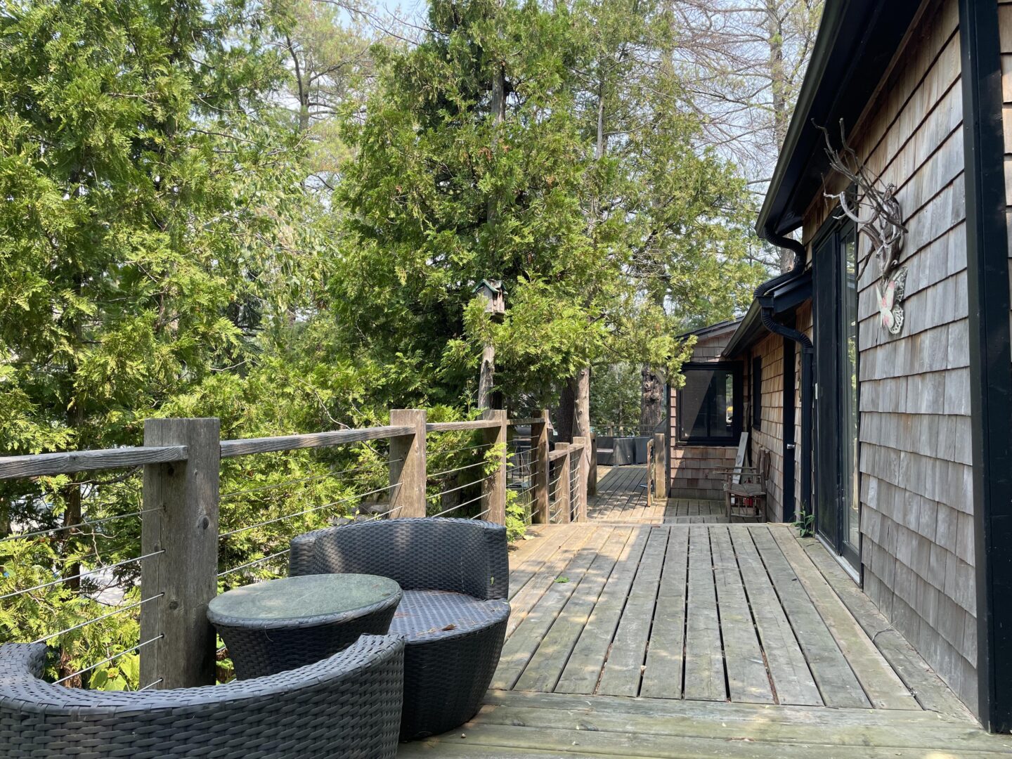 A wood deck with a small sitting area outside a wood cabin
