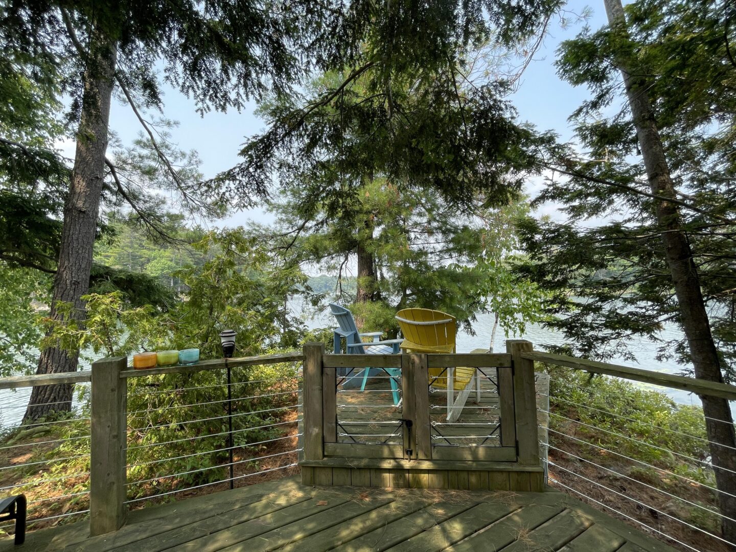 A wood deck with two Muskoka chairs looking out to the water