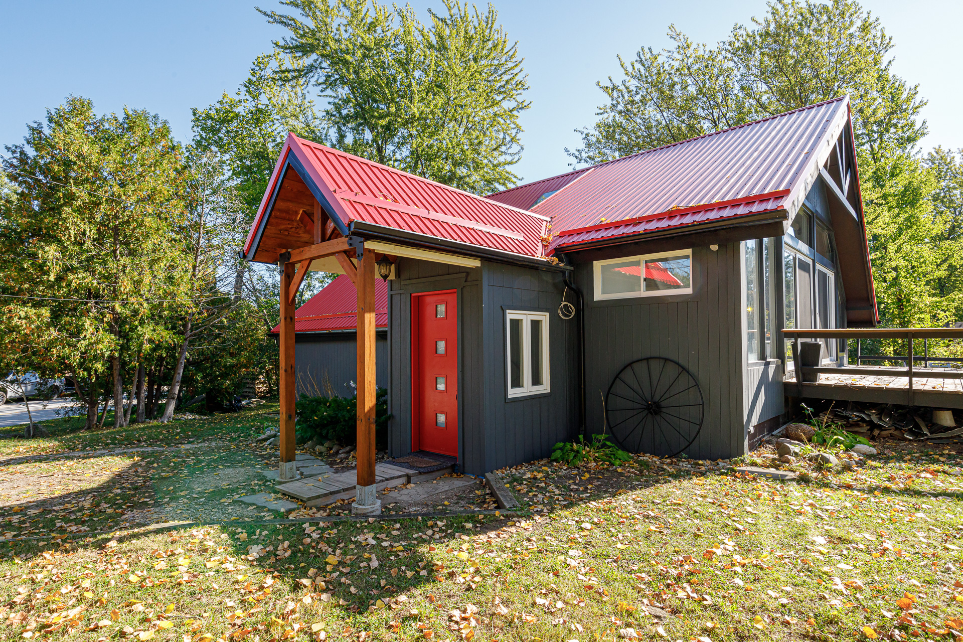A black cottage with a red roof and a red front door