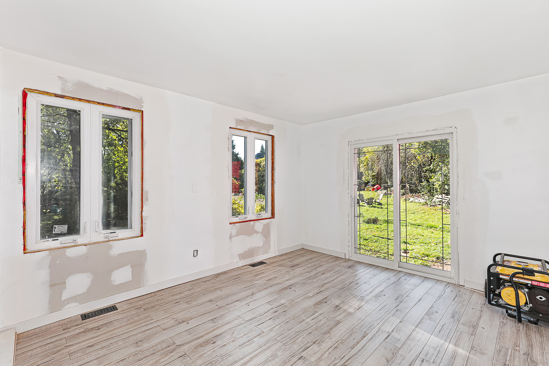 An empty white bedroom with bright windows that look onto the property