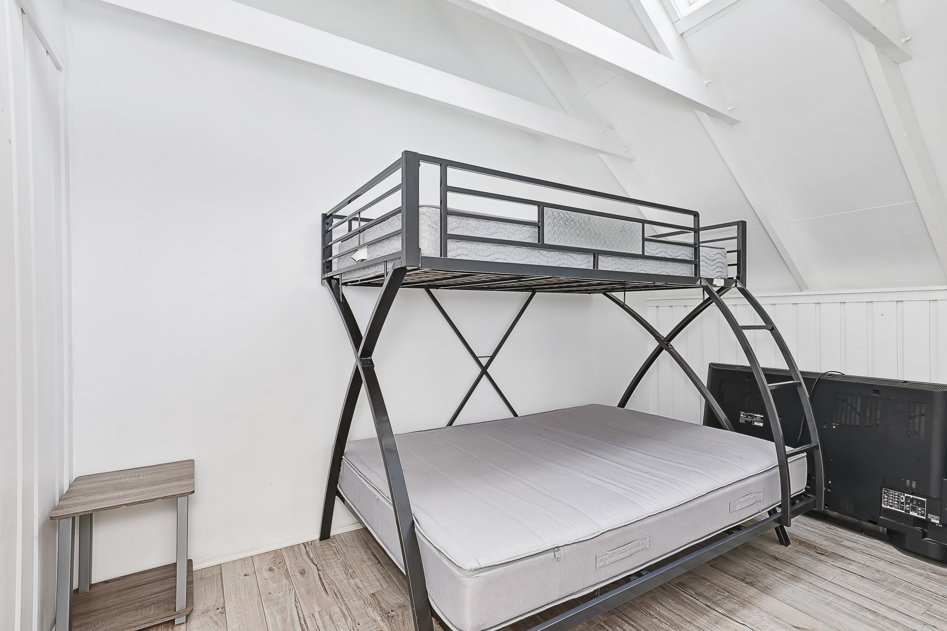 A white bedroom with metal bunk beds and uncovered mattresses