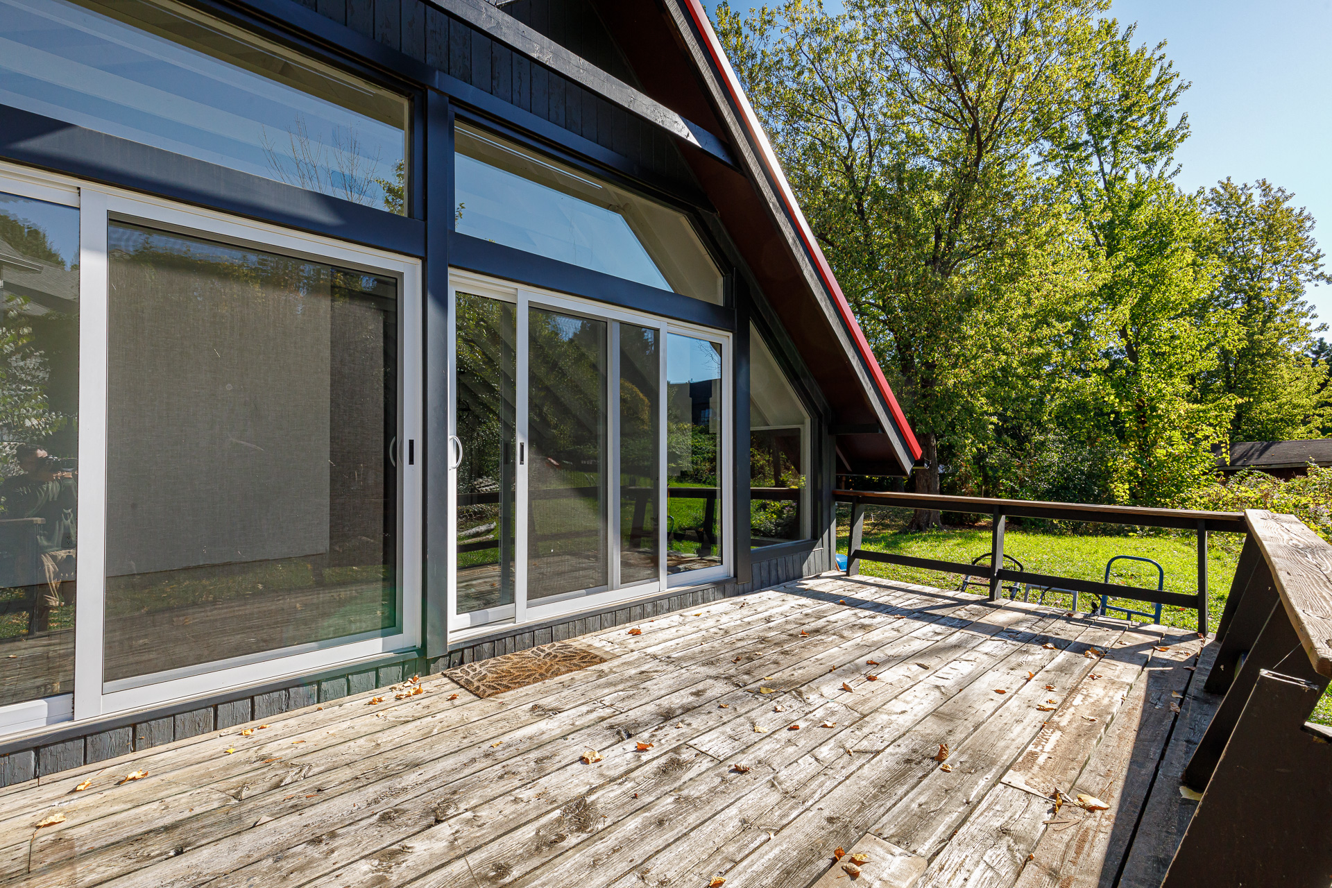A deck on the back of a black cottage with sliding doors