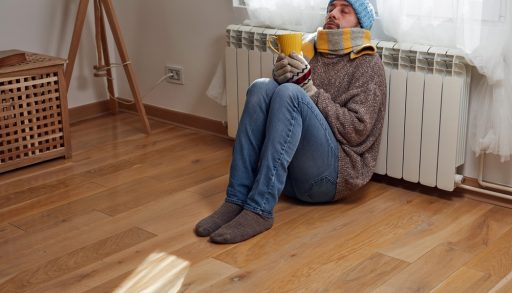 A man huddled at a thermostat