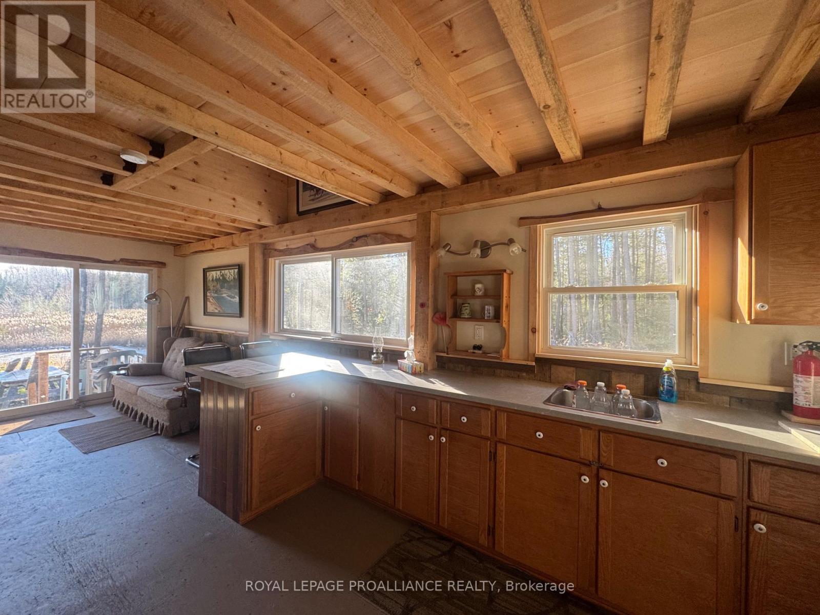An L-shaped kitchen with wood cabinets and an unfinished wood ceiling
