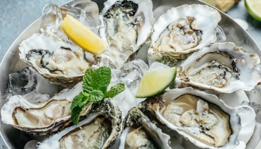 Fresh oysters in a platter, on ice, with lemon wedges