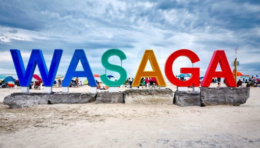 Colourful giant Wasaga beach sign sitting on big rocks at Ontario famous popular summer travel destination Wasaga beach near Georgian Bay. Its long, sandy beach lies on Nottawasaga Bay.