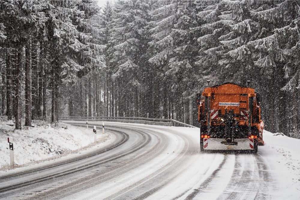 An orange truck clearing a road and applying salt