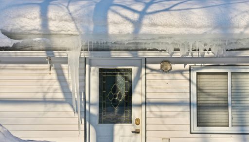 A small house with heavy snow load and lots of icicles