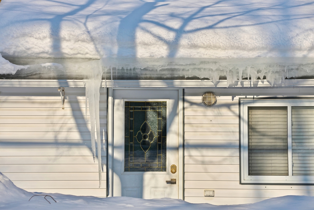 A small house with heavy snow load and lots of icicles
