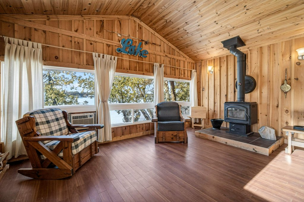 Warm wood-lined living room with large windows, seating area, and views toward the lake.