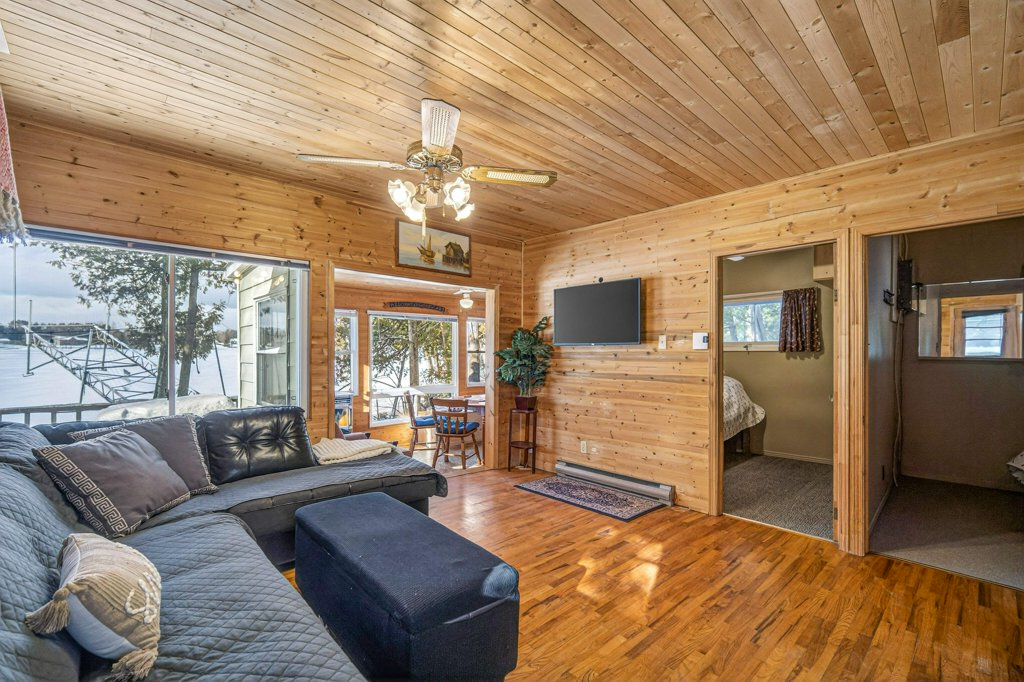 Comfortable sitting room with wood walls, large windows, sectional seating, and warm natural light.