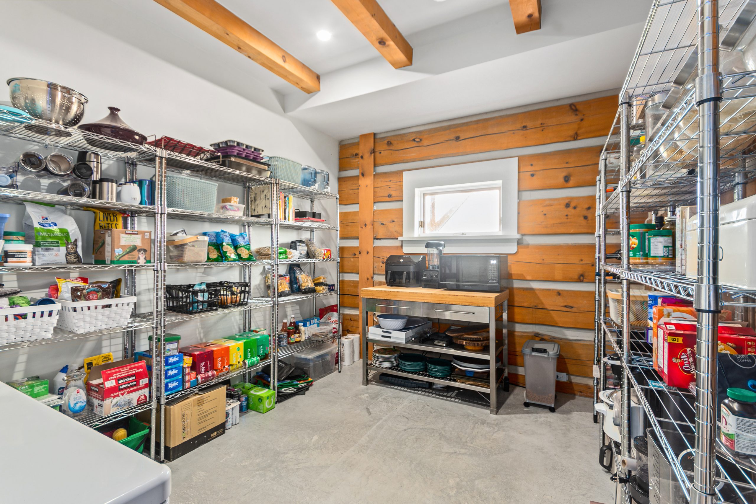 Walk-in pantry with metal shelving stocked with pantry items, plus additional storage and prep space.