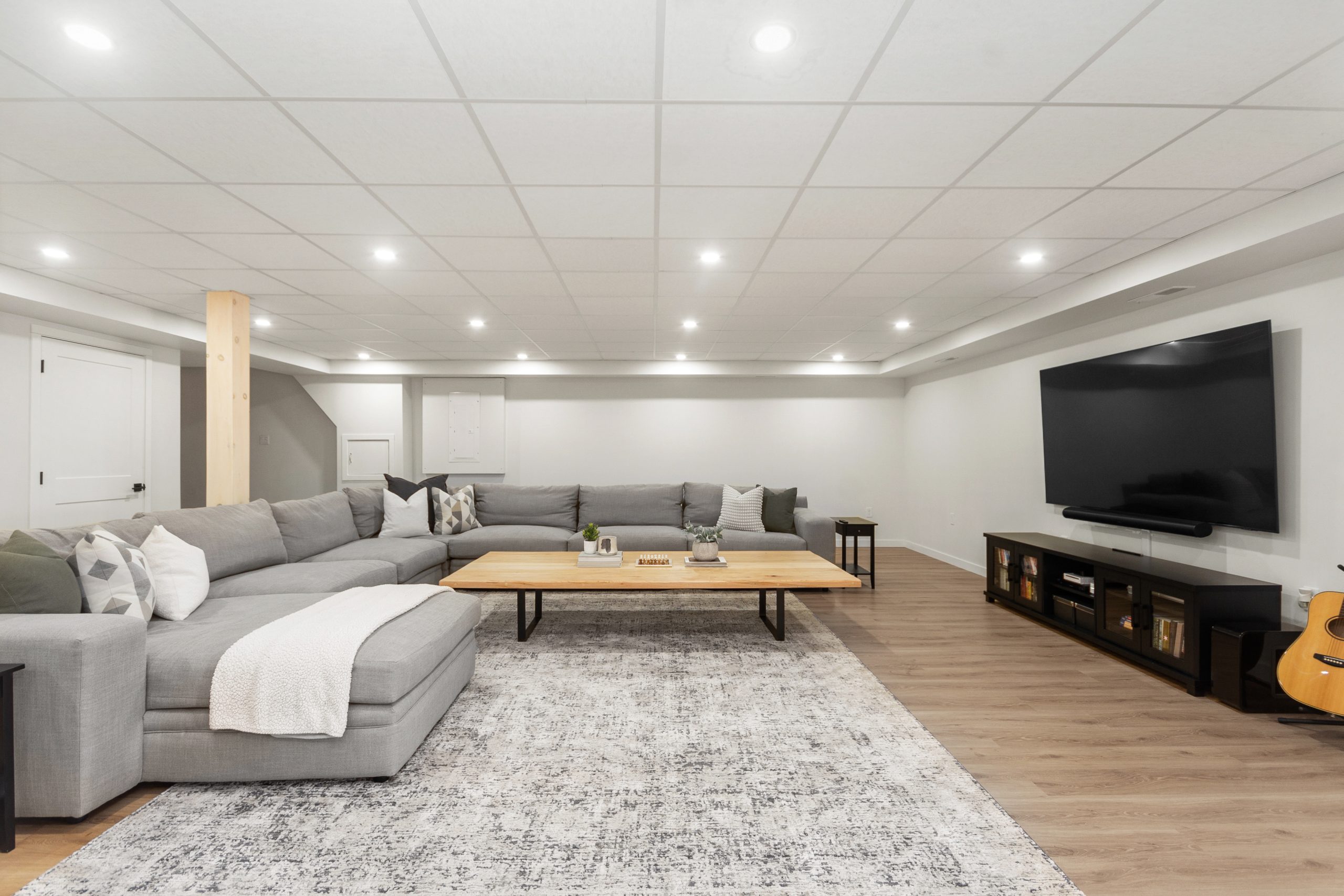 Finished lower-level family room with a large sectional sofa, wall-mounted TV, and recessed lighting.