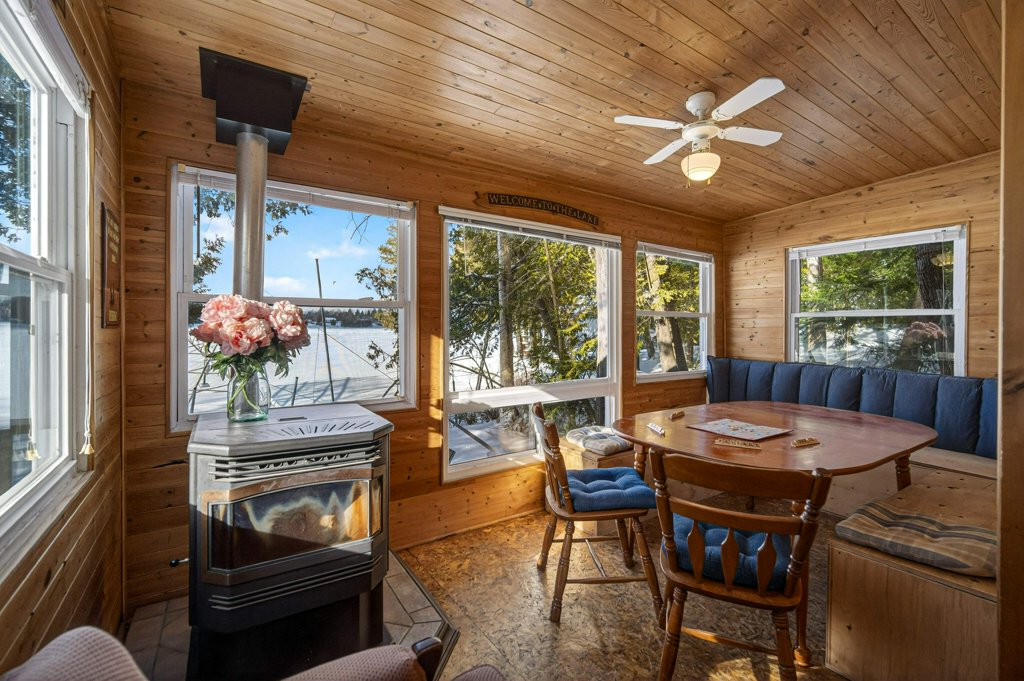 Cozy dining area with wood interior, pellet stove, and windows overlooking the waterfront.