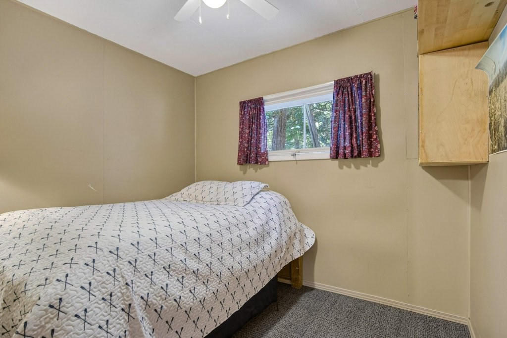 Compact bedroom with beige walls, double bed, window, and built-in storage.