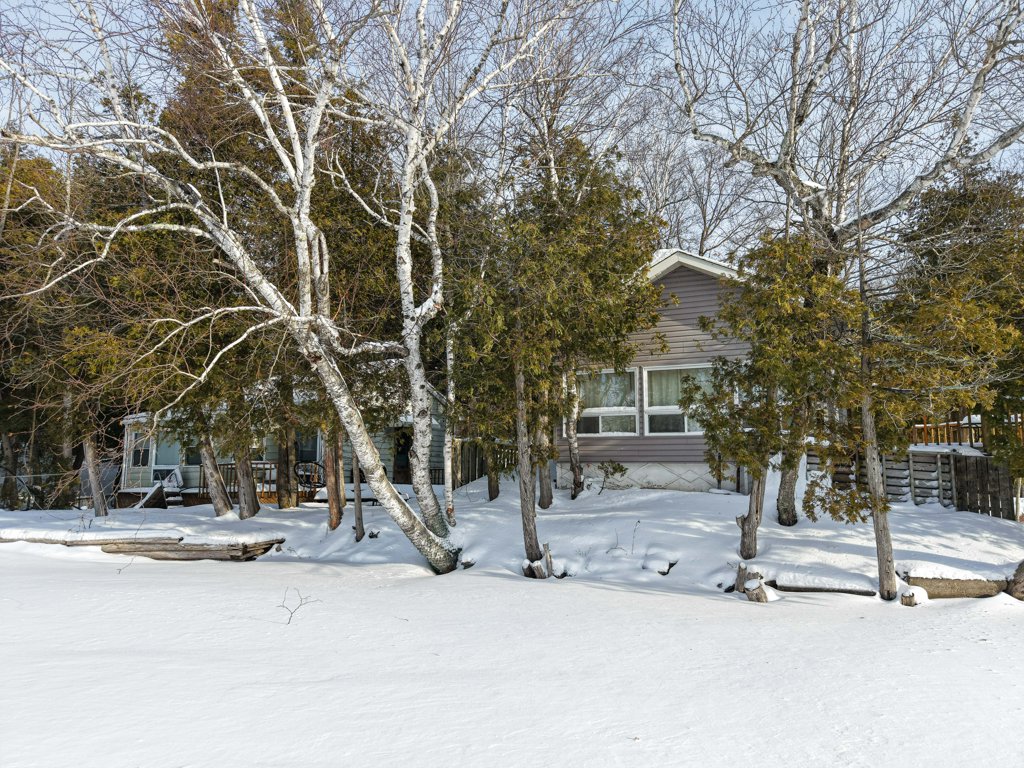 Exterior view of the cottage from the frozen shoreline of Beaver Lake in winter.
