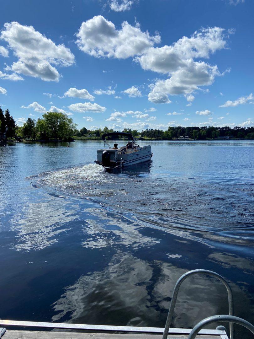 Boat cruising across Beaver Lake under a bright blue sky with scattered clouds.