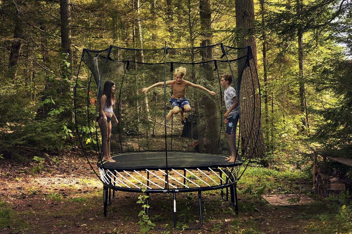 Kids jumping on an outdoor trampoline with a net