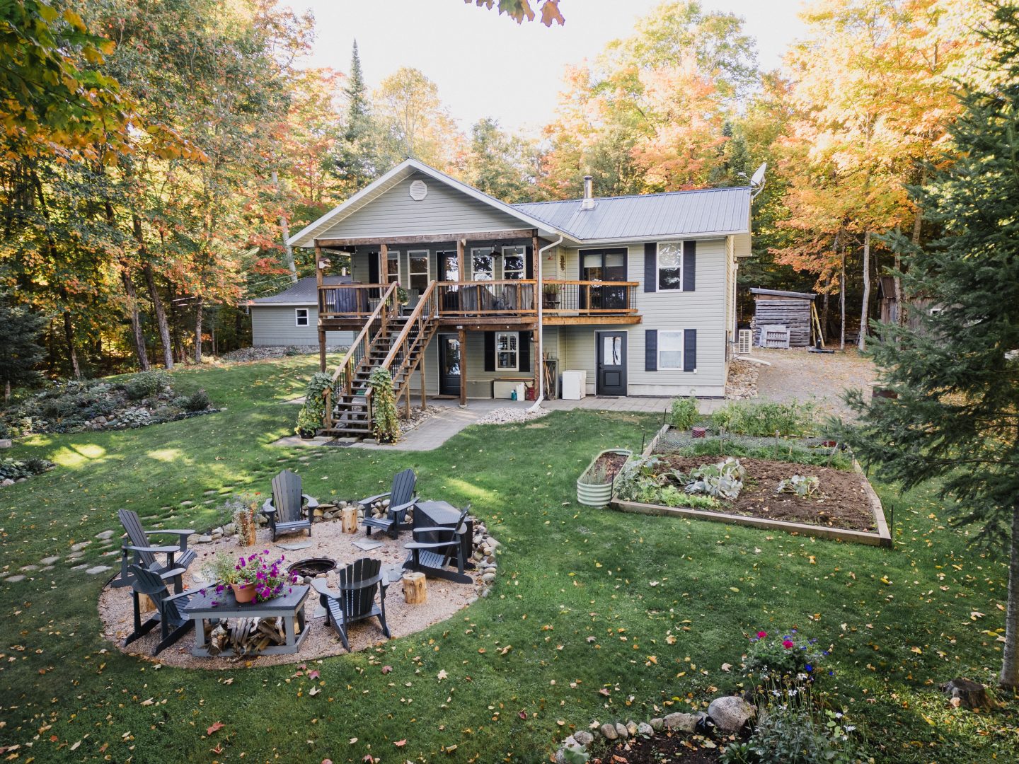 A spacious cottage property with a grassy backyard and a fire pit area