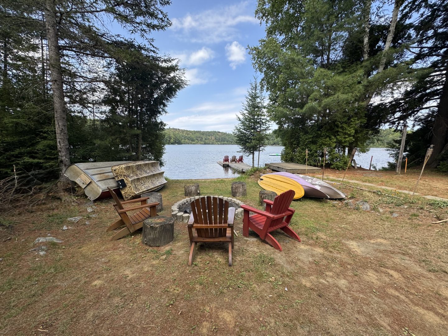 A lakeside fire pit with Muskoka chairs surrounding