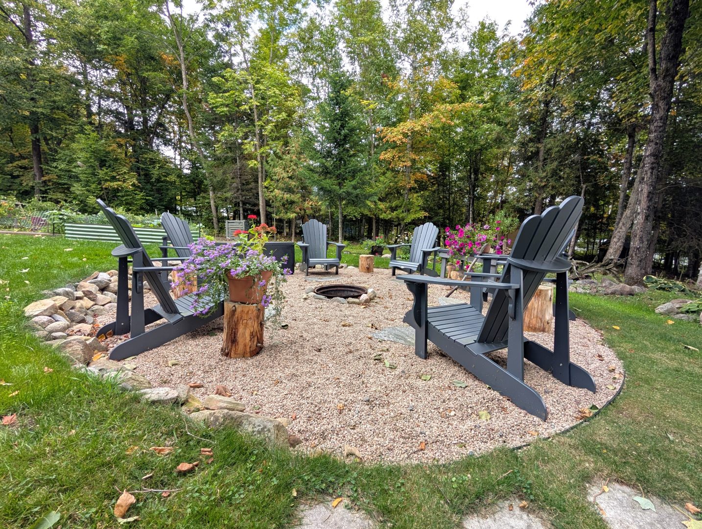 Muskoka chairs on a circle of patio stones facing a fire pit